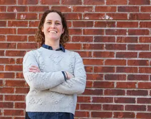 Consultant Ally Johnston standing in front of a brick wall.