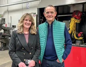 Lori Kloos and Bob Kill standing in front of a machine.