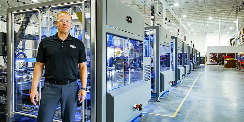 Delkor's VP of Engineering, Rick Gessler in front of ten Trayfecta case former/erectors ready for shipment. 