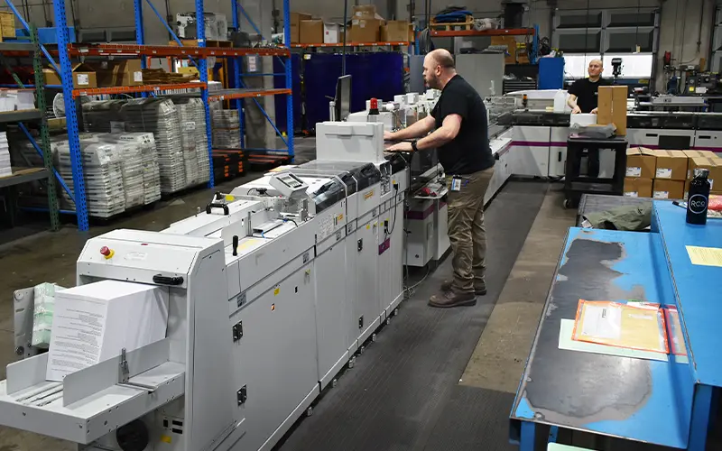 Drew McDougle, Mailing Operator running one of the Toppan Merrill envelope-inserting devices for personalized communications mail prep.