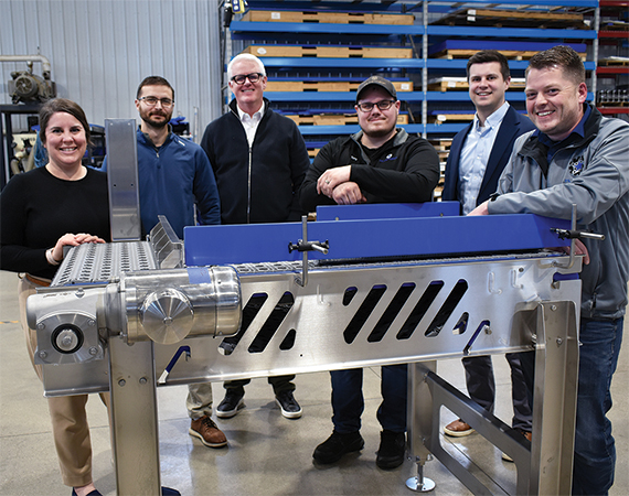 Enterprise Minnesota business development consultant Andrew Busta and colleagues pose with InLine Motion leaders around a stainless steel conveyor system inside the company's Detroit Lakes, Minnesota manufacturing facility.