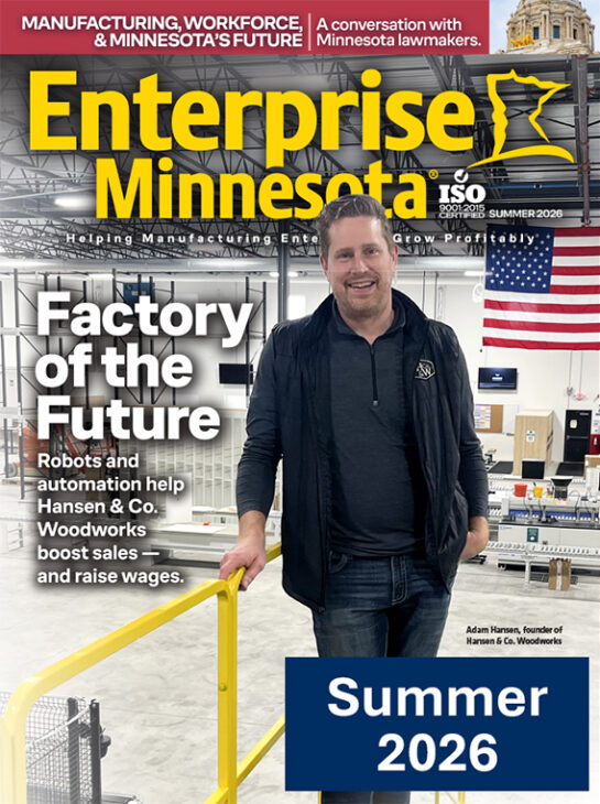 Magazine cover of Enterprise Minnesota Summer 2026 issue featuring Adam Hansen, founder of Hansen & Co. Woodworks, standing in a modern manufacturing facility with robotic automation equipment and an American flag in the background.