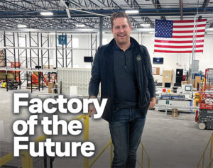 Hansen & Co. Woodworks founder and president Adam Hansen stands on an elevated platform overlooking the expansive floor of his new 92,000-square-foot automated manufacturing facility, with an American flag hanging in the background.