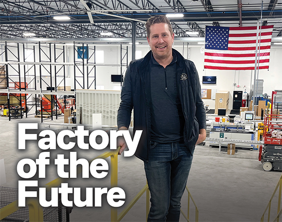 Hansen & Co. Woodworks founder and president Adam Hansen stands on an elevated platform overlooking the expansive floor of his new 92,000-square-foot automated manufacturing facility, with an American flag hanging in the background.