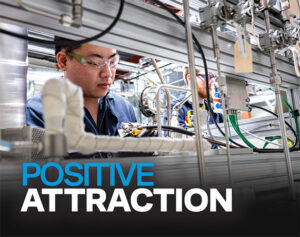A technician wearing safety glasses works intently among stainless steel tubing and equipment at Niron Magnetics' manufacturing facility.