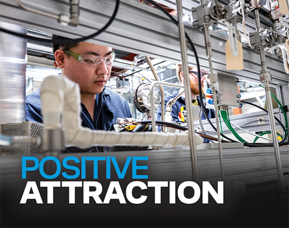 A technician wearing safety glasses works intently among stainless steel tubing and equipment at Niron Magnetics' manufacturing facility.