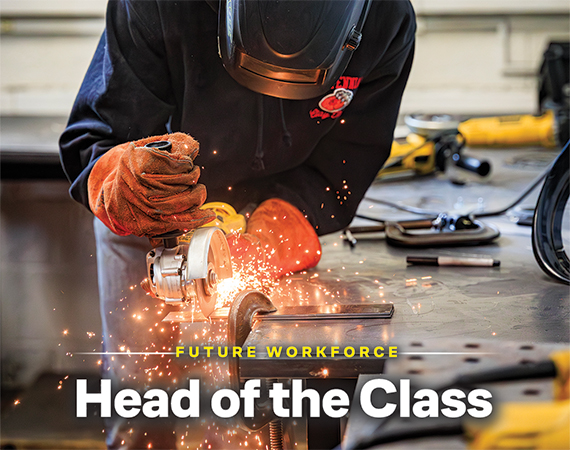 Student wearing welding gloves and face shield grinding metal in a high school shop class, sparks flying.