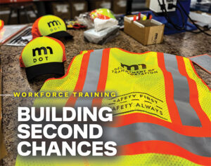High-visibility MnDOT safety vests and hats manufactured by MINNCOR workers, displayed on a workbench.