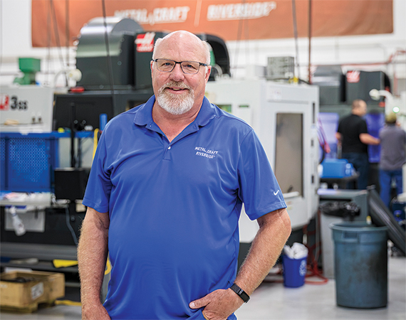 John Bolanda, training specialist at Metal Craft & Riverside, standing on the manufacturing production floor.