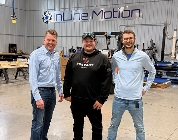 InLine Motion's leadership team standing on the manufacturing production floor beneath the company sign.